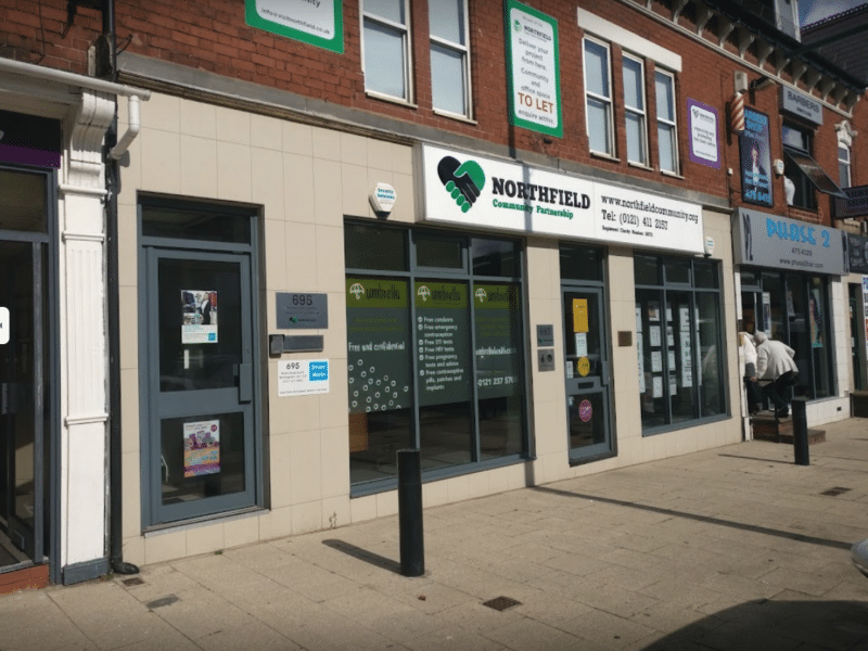 Light grey building with a sign for 'Northfield Community Partnerhsip' by the front.